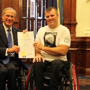 Kirk, getting a certificate awarded by another man in a wheelchair