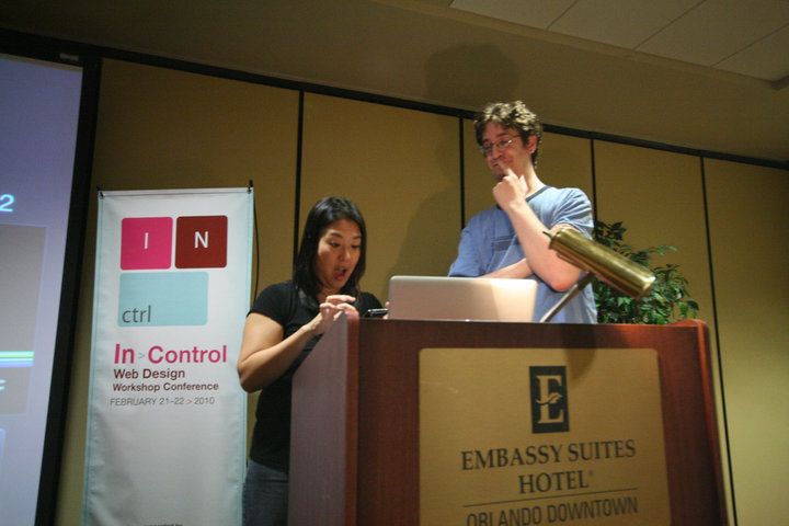 Christopher Schmitt smiling as Kelly Goto looks amazed at a phone at the 2010 Web Control Web Design Workshop Conference